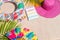 Colourful writing note pad with pink and green pen on sand, surrounded by green palm leafs, sea shells, pink hat, inflatable toys