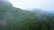 Column of hikers on a foggy green part of mountain above the trees - mystical magical scene