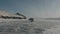 Column of minibuses UAZ at high speed ride on the transparent ice of Lake Baikal past the rocky mountains on the coast