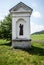 Column shrine with tree on the background, meadow and narrow road near Milesov village in Czech republic