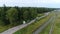 A column of trucks drives along a winding country road.