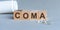 COMA is a word written in black letters on wooden cubes