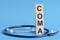 Coma word written on wooden blocks and stethoscope on light blue background