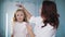 comb child hair. mom is combing her little daughter's hair, doing her hair. woman and little girl stand in front of the