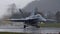 Combat airplane take off in the rain with light reflexions on the runway