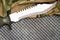 Combat knife on military camouflage fabric and metal background