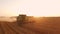 Combine harvester, field and sunrise.