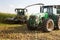 Combine harvester mowing corn on farm field and pouring into truck