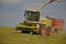 Combine harvester mows the field, harvester unloading into a tractor trailer