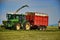 Combine harvester mows the field, harvester unloading into a tractor trailer