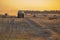 Combine harvester pressing straw field bales driving field sunny summer evening