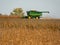 Combine Harvester scooping up corn stalks in field