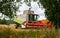 Combine harvester stands between trees wheat field