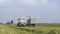 Combine harvester and tractor-trailer working in field, harvesting feed crop. Combine mechanically collects fresh crop