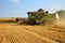 Combine harvester working on a golden ripe wheat field on a bright summer day. Lot of grain dust in the air