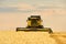 Combine harvester working in wheat field with cloudy moody sky. Harvesting machine driver cutting crop in a farmland