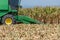 Combine harvesters are working in corn fields. Harvesting of corn field with combine in early autumn.