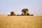 Combine harvesters working in a wheat field on sunset round about. Harvesting machine driver cutting crop in a farmland