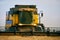 Combine harvesters working in a wheat field on sunset round about. Harvesting machine driver cutting crop in a farmland