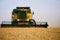 Combine harvesters working in a wheat field on sunset round about. Harvesting machine driver cutting crop in a farmland