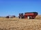 Combine harvesting a corn field and loading a grain cart while a 2nd tractor and grain cart waits in Northern Illinois