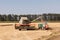 Combine harvesting wheat and unloading grains into tractor trailer