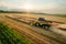 Combine reaper with dust flow cuts ripe barley in farm field