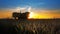 Combine tractor in field harvesting at sunset