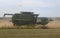 Combine Tractor Harvesting Ripe Wheat in a Field with Dust Flying through the Air