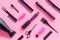 Combs, dryer, sciccors and hairdresser tools in beauty salon work desk on pink background top view pattern