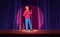 Comedy live show with male comic, funny guy in hoodie, hat standing in spotlight on stage