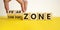 Comfort or fear zone symbol. Hand turns wooden cubes and changes words `comfort zone` to `fear zone`. Beautiful yellow table,