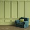 Comfortable armchair emerald color with green pillow standing in classic interior. Green walls with mouldings,floor parquet oak He