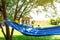 Comfortable blue hammock with hat and book on sunny day