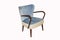 Comfortable blue velours armchair with armrests on white background. Interior element