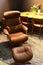 Comfortable brown coloured padded leather chair made by Kratz, with leg-rest placed in front of dinner table on Furniture Expo