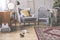 Comfortable grey armchair with yellow pillow between retro cabinet and wooden crib in mid century baby room interior