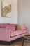 Comfortable velvet pastel pink couch in elegant beige interior with abstract painting