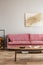 Comfortable velvet pastel pink couch in elegant beige interior with abstract painting