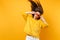 Comic young girl in fur sweater holding heart orange glasses fooling around in studio jumping with flying hair isolated