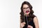 Comical curly young female playing with glasses and moustache booth
