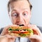 Comical man eating sandwich with funny expression