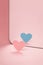 Coming out. Pink paper heart in front of a mirror. Blue heart reflected.