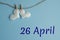 Commemorative date April 26 on a blue background with white hearts with clothespins, flat lay. Holiday calendar concept