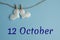 Commemorative date October 12 on a blue background with white hearts with clothespins, flat lay. Holiday calendar