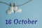 Commemorative date October 16 on a blue background with white hearts with clothespins, flat lay. Holiday calendar