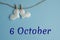 Commemorative date October 6 on a blue background with white hearts with clothespins, flat lay. Holiday calendar concept