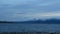 Commercial airplane coming in for landing over snowy mountain peaks and open blue fjord in early winter