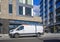 Commercial compact mini van for small business and deliveries standing on urban city street with multilevel apartments buildings