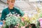 Commercial gardener woman taking care of her potted flowers